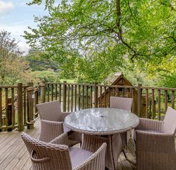 An outdoor dining area with a circular table and chairs at The Treehouse in Praze-An-Beeble