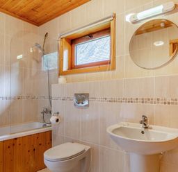 A bathroom with a bathtub, toilet, and sink at Woodland Lodge Spa, Praze-An-Beeble