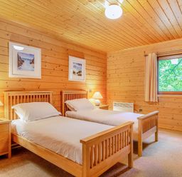 A bedroom with two single beds and a nightstand at Woodland Lodge Spa Praze-An-Beeble