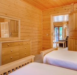 A bedroom with a dresser and two beds at Woodland Lodge Spa in Praze-An-Beeble