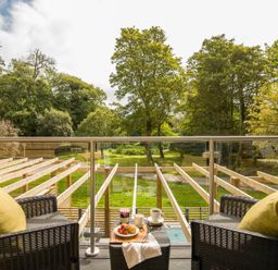 A balcony with chairs and a table overlooking a garden at Kilden Pet in Praze-An-Beeble