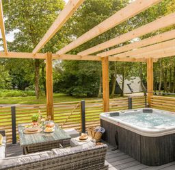 A patio with a hot tub and outdoor furniture at Kilden Pet in Praze-An-Beeble