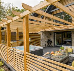 A patio area with a hot tub and dining furniture at Kilden Pet in Praze-An-Beeble