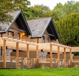A wooden house with a balcony and pergola at Kilden Pet in Praze-An-Beeble