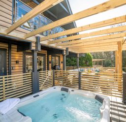 An outdoor area with a hot tub and dining set at Lowarth Lodge Spa Pet Praze-An-Beeble
