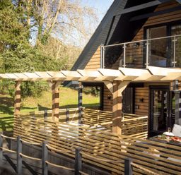 An outdoor deck with a pergola and railing at Lowarth Lodge Spa Pet in Praze-An-Beeble