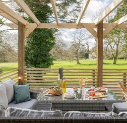 An outdoor patio with seating and dining items at Lowarth Lodge Spa Pet in Praze-An-Beeble