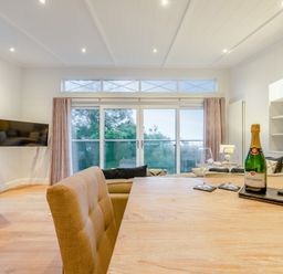 A living room with a dining table and champagne at Milk Wood 2 in Laugharne
