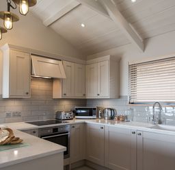 A kitchen with cabinets, sink, stove, and fruits at Dylan Spa in Laugharne