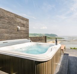 A hot tub on a wooden deck with a view of the landscape at The View in Laugharne