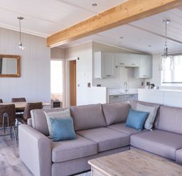 A living room with a sofa and dining table at Milk Wood 3 Spa in Laugharne