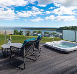 An outdoor area with a hot tub and chairs at Apex Spa in Laugharne