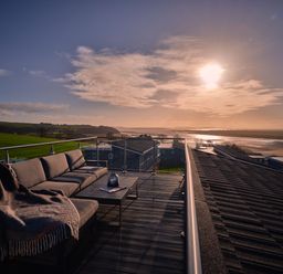 A terrace with a sofa and table overlooking a river at Sonnet 3 Roof Terrace Spa in Laugharne