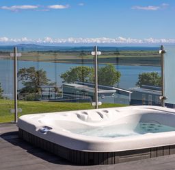 A hot tub with a view of a lake at Apex Spa (Pet) Laugharne