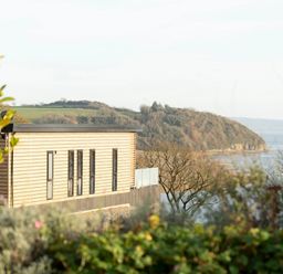 A building with a glass railing overlooking trees and hills at Solace in Laugharne