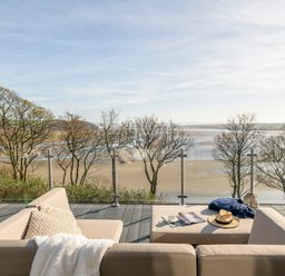An outdoor seating area with a couch and coffee table overlooking the water at Solace in Laugharne