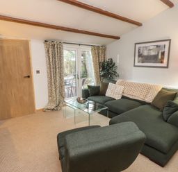 A living room with a green couch and glass coffee table at 20 Chatham Log Cabins Caernarfon