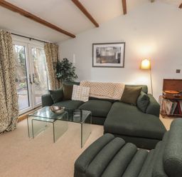 A living room with a green sofa and glass coffee table at 20 Chatham Log Cabins in Caernarfon