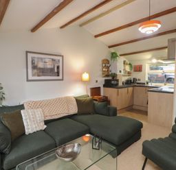 A living room with a sofa and kitchen area at 20 Chatham Log Cabins in Caernarfon