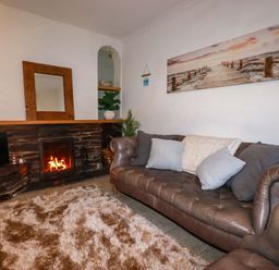 A living room with a sofa and fireplace at Chapel Cottage in Mevagissey