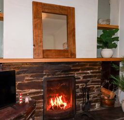 A living room with a fireplace and mirror at Chapel Cottage in Mevagissey