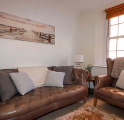 A living room with a sofa and armchair at Chapel Cottage in Mevagissey