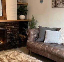 A living room with a sofa and a fireplace at Chapel Cottage in Mevagissey