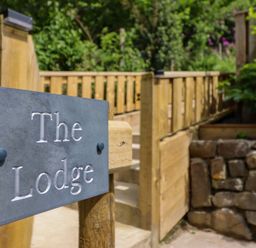 A sign for The Lodge in an outdoor area near steps and a stone wall at Lodge at Nadur Commins Coch near Machynlleth
