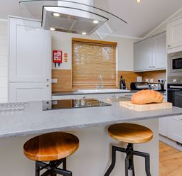 A kitchen with an island and stools at The Folkesworth in Kings Cliffe