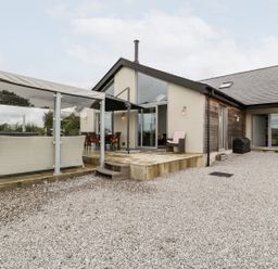 An outdoor area with seating and a glass enclosure at Cae Sam in Pentraeth
