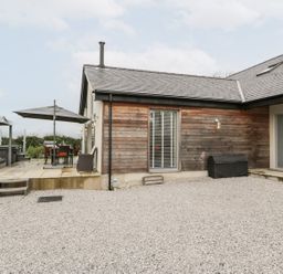 An outdoor area with a house, patio set, and gravel at Cae Sam Pentraeth