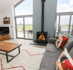 A living room with a fireplace and television at Cae Sam in Pentraeth