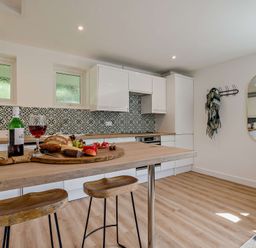 A kitchen with a table set with wine and fruits at Klys 1.0 Spa in Perranporth