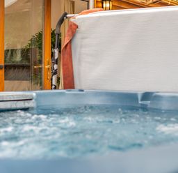 A hot tub next to a wooden cabin at Piran Spa Lodge Pet Perranporth