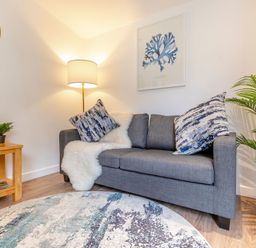 A living room with a sofa and lamp at Chapel Rock Spa Pet in Perranporth