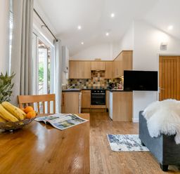 A kitchen with wooden cabinets and a dining area at Droskyn Spa Pet in Perranporth