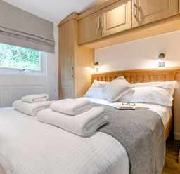 A bedroom with a bed, towels, and wardrobe at Morva Spa Pet in Perranporth