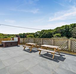 An outdoor patio with a hot tub and picnic table at The Farmhouse (Pet) Perranporth