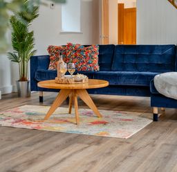 A living room with a blue sofa and a round coffee table at The Farmhouse (Pet) Perranporth