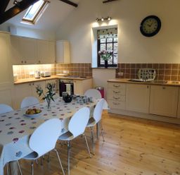 A kitchen with a dining table and chairs at Nethercote Byre in Minehead