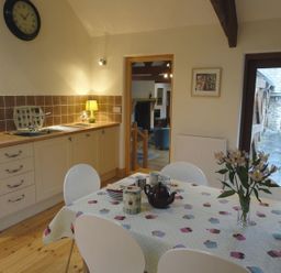 A kitchen with a table and chairs at Nethercote Byre in Minehead
