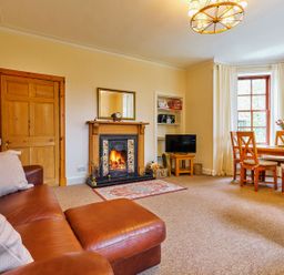 A living room with a fireplace and dining area at West Lodge in Kirriemuir