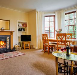 A living room with a fireplace and dining area at West Lodge in Kirriemuir