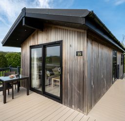 A wooden cabin with a table and chairs outside at Stokesley (Pet) Great Ayton