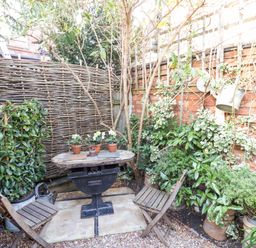 A garden with a table and chairs surrounded by plants at Flat 4 in Evesham