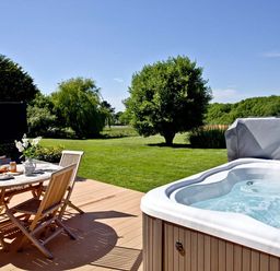 A garden with a hot tub and dining table at 4C2 Summerleaze Garden Cottage 2 Spa Bude