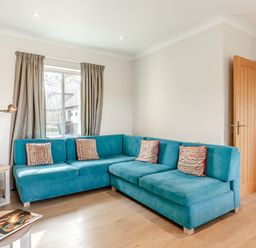 A living room with a blue sofa and a table at 4C2 Summerleaze Garden Cottage 2 Spa in Bude