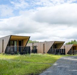 Three wooden cottages set in grassy area at Orka 1.0 (Pet) Dumfries