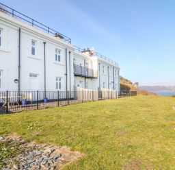 A building with a fenced outdoor area and grass at The Old Signal House in Torpoint