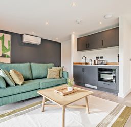 A living room with a sofa and kitchen area at Arvor Suite 1.0 Marhamchurch